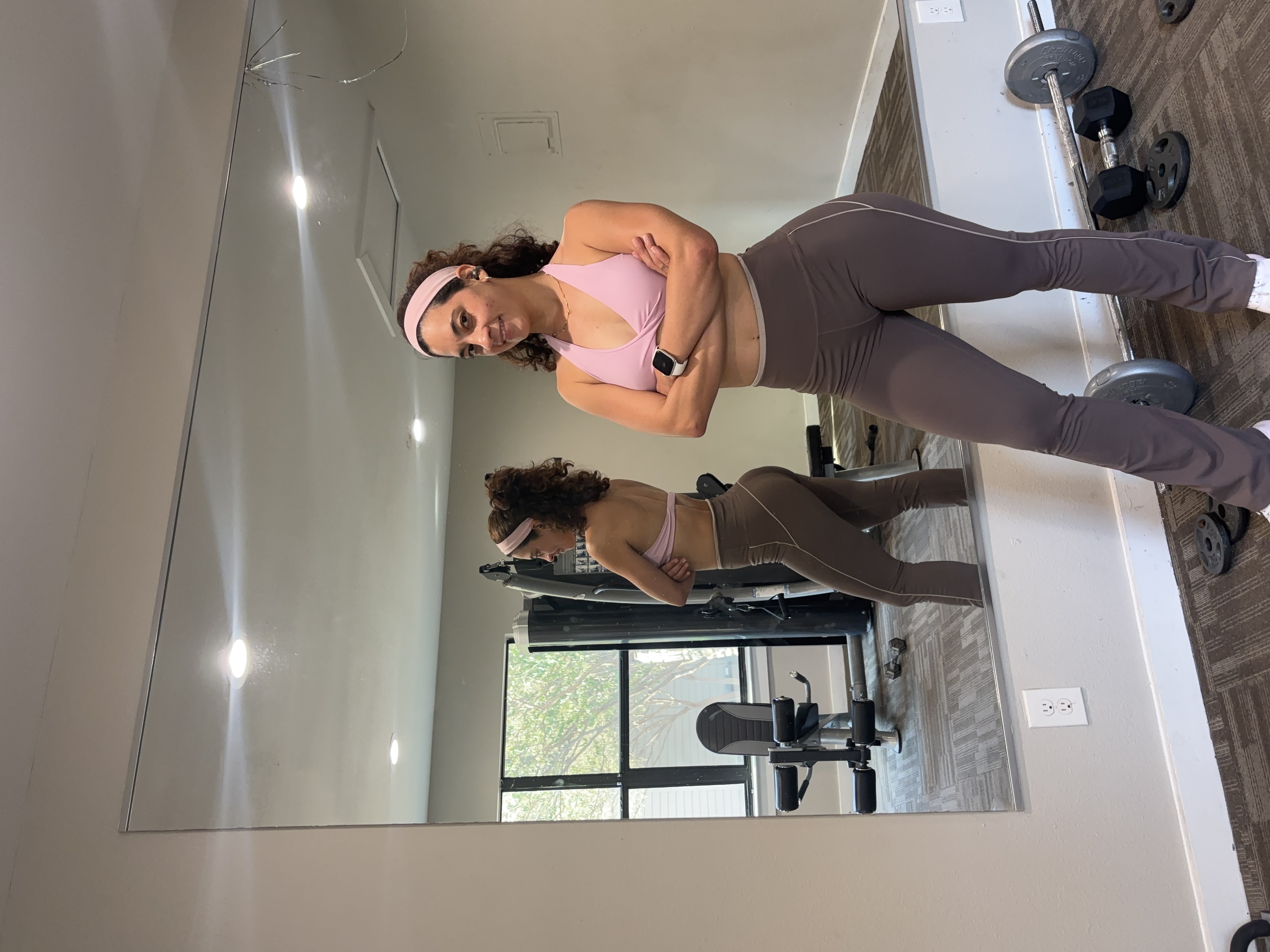Iviancy Fuentes standing in her Austin training studio beside the mirror and dumbbells